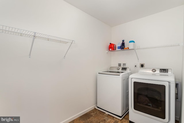 laundry area featuring separate washer and dryer, baseboards, laundry area, and stone finish flooring