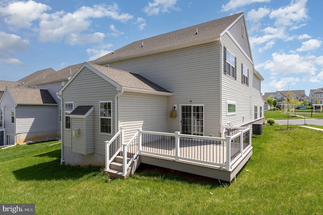 back of property with a yard, a deck, central AC unit, and a shingled roof