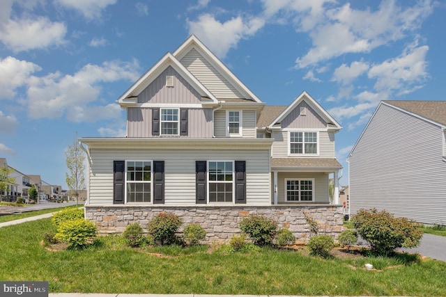 craftsman house with board and batten siding, a front lawn, and stone siding