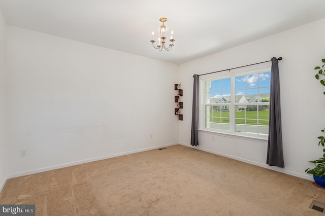 carpeted spare room with visible vents, baseboards, and a chandelier