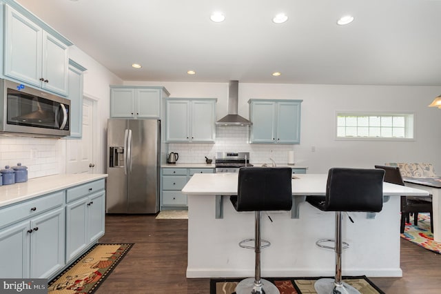 kitchen with light countertops, backsplash, stainless steel appliances, and wall chimney exhaust hood