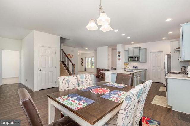 dining area featuring dark wood finished floors, recessed lighting, stairs, and a chandelier