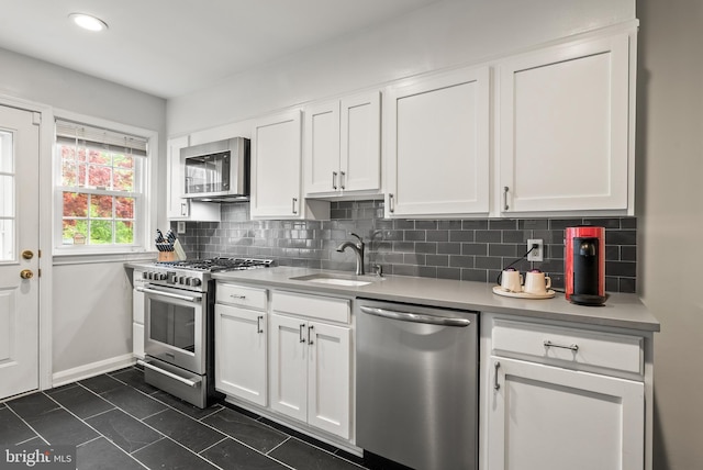 kitchen with appliances with stainless steel finishes, a sink, light countertops, white cabinetry, and tasteful backsplash