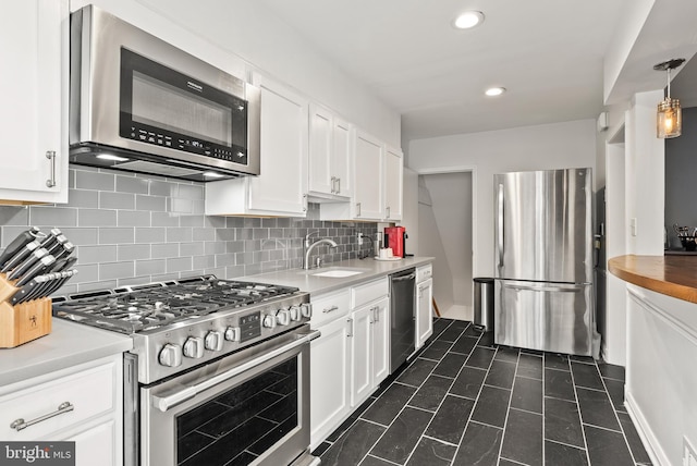 kitchen with a sink, white cabinets, stainless steel appliances, and tasteful backsplash