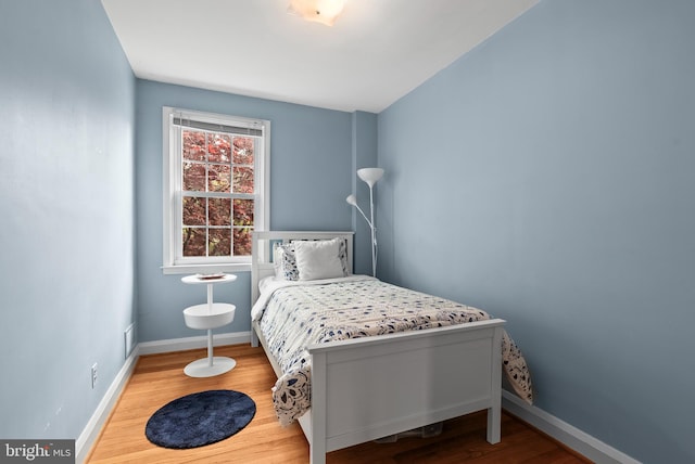 bedroom with baseboards, visible vents, and wood finished floors