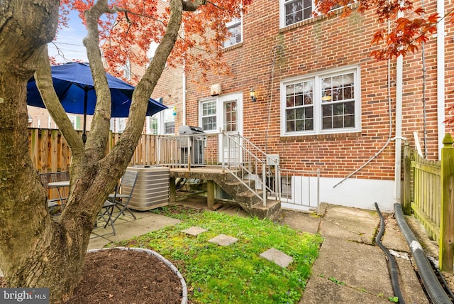 rear view of property with fence, central AC, and brick siding