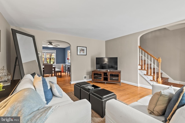 living room featuring visible vents, arched walkways, ceiling fan, and wood finished floors