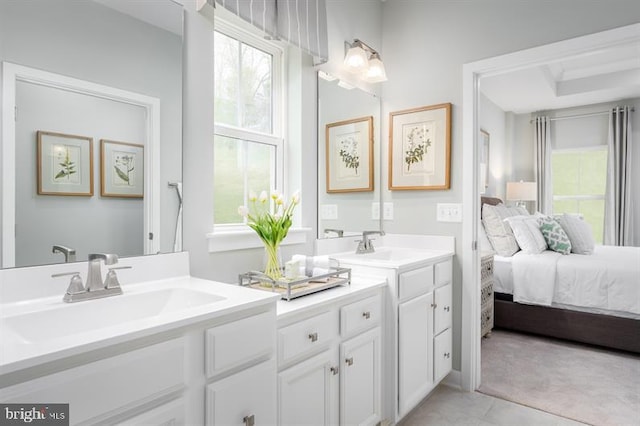 ensuite bathroom featuring double vanity, a sink, a wealth of natural light, and connected bathroom