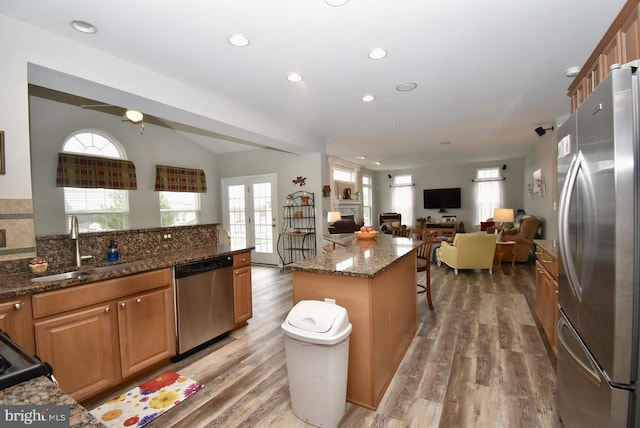 kitchen with light wood-style flooring, a sink, a breakfast bar area, and appliances with stainless steel finishes