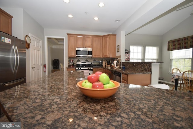kitchen featuring tasteful backsplash, recessed lighting, dark stone counters, appliances with stainless steel finishes, and a sink