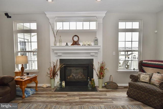 living area with baseboards, recessed lighting, wood finished floors, and a fireplace with flush hearth