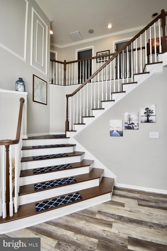 staircase featuring ornamental molding, recessed lighting, visible vents, and wood finished floors