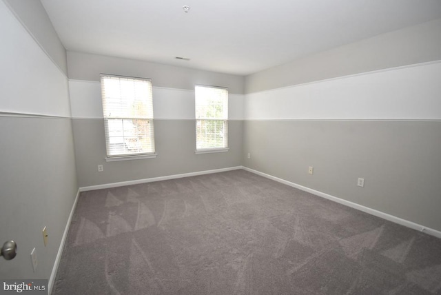 spare room featuring baseboards, visible vents, and carpet floors