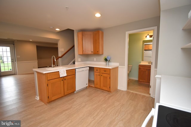 kitchen featuring a sink, light countertops, light wood-type flooring, dishwasher, and a peninsula