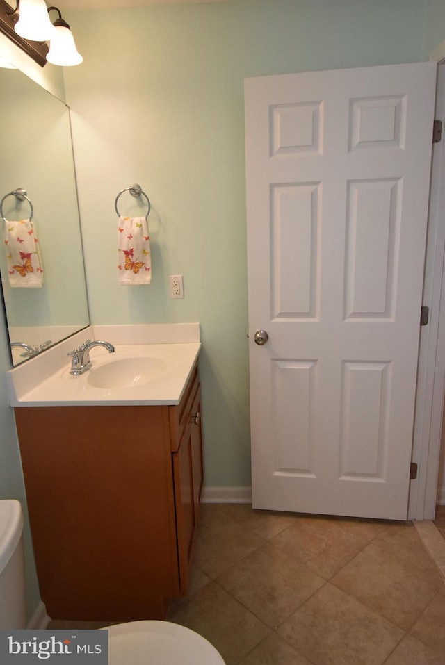 half bath featuring vanity, toilet, tile patterned flooring, and baseboards