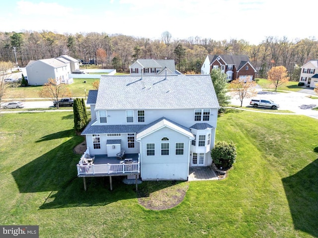 back of property with a yard, a shingled roof, and a wooden deck