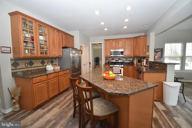 kitchen featuring a breakfast bar area, a sink, appliances with stainless steel finishes, and wood finished floors