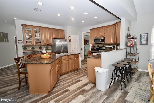 kitchen with a breakfast bar area, tasteful backsplash, a center island, and appliances with stainless steel finishes
