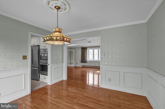 unfurnished dining area with a baseboard radiator, a wainscoted wall, and ornamental molding