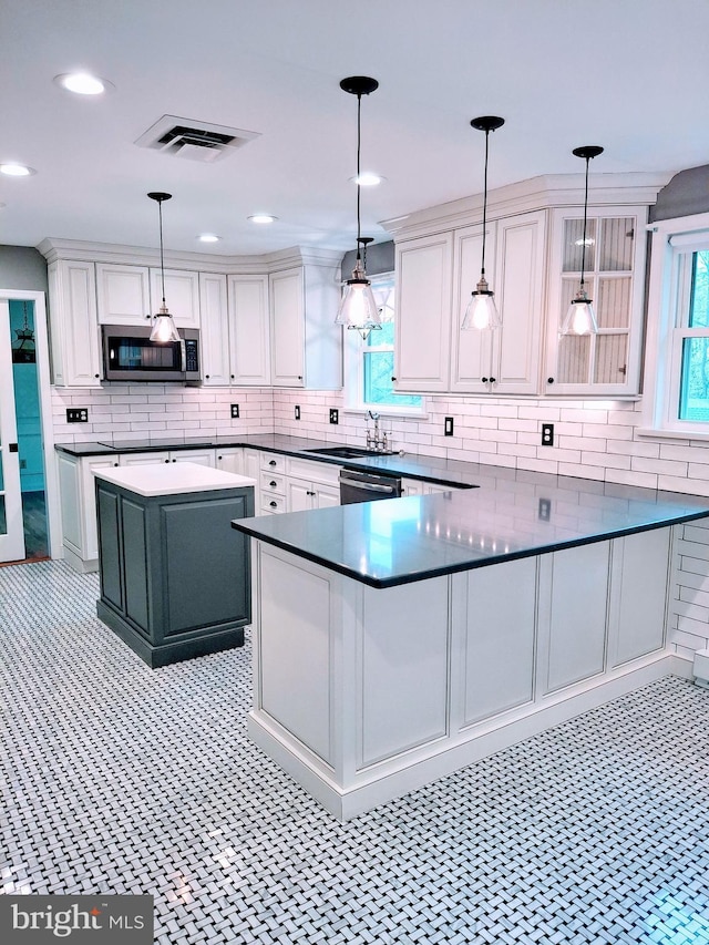 kitchen featuring white cabinetry, tasteful backsplash, a sink, appliances with stainless steel finishes, and visible vents