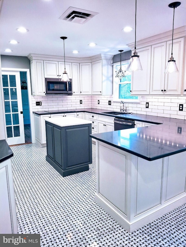 kitchen featuring dark countertops, a sink, decorative backsplash, and stainless steel microwave