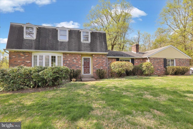 colonial inspired home with entry steps, roof with shingles, mansard roof, brick siding, and a front lawn