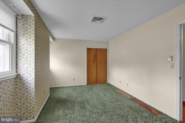 carpeted spare room with visible vents and baseboards