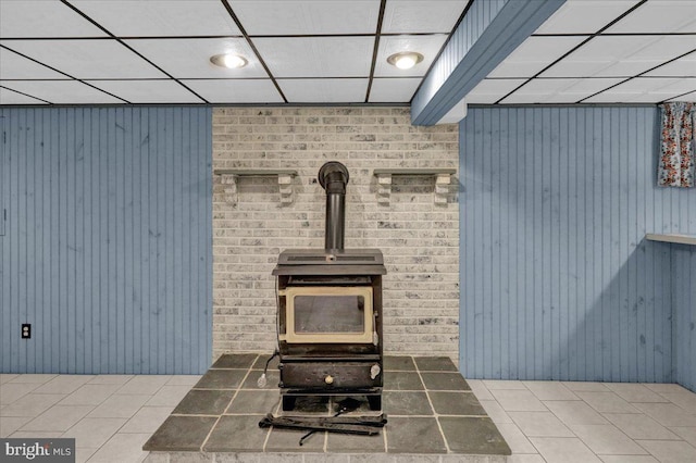 room details with a wood stove and a drop ceiling