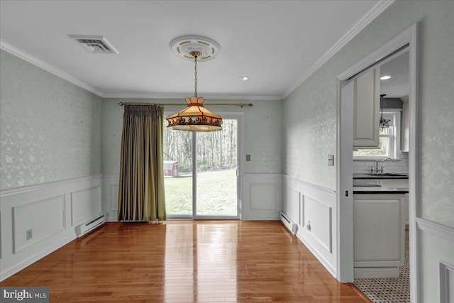unfurnished dining area featuring light wood-style flooring, a baseboard radiator, a baseboard heating unit, a wainscoted wall, and visible vents