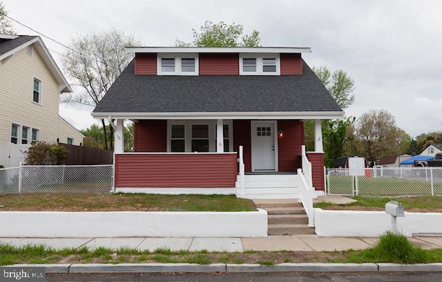 bungalow-style home with roof with shingles, covered porch, and fence private yard