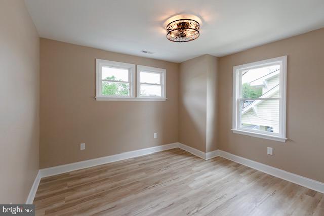 spare room with baseboards and light wood-style flooring