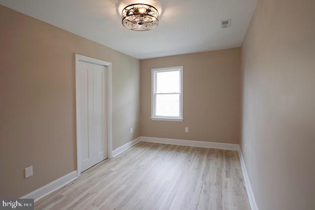 spare room featuring baseboards, light wood finished floors, and visible vents