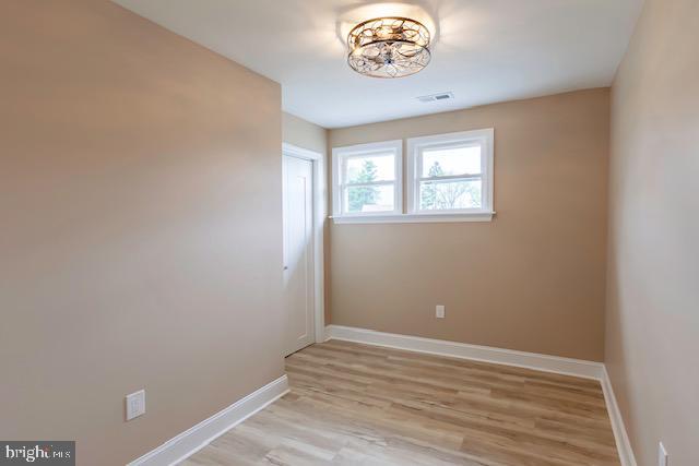 unfurnished room with baseboards, light wood-type flooring, and visible vents