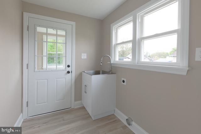 laundry room featuring hookup for an electric dryer, laundry area, baseboards, and a sink