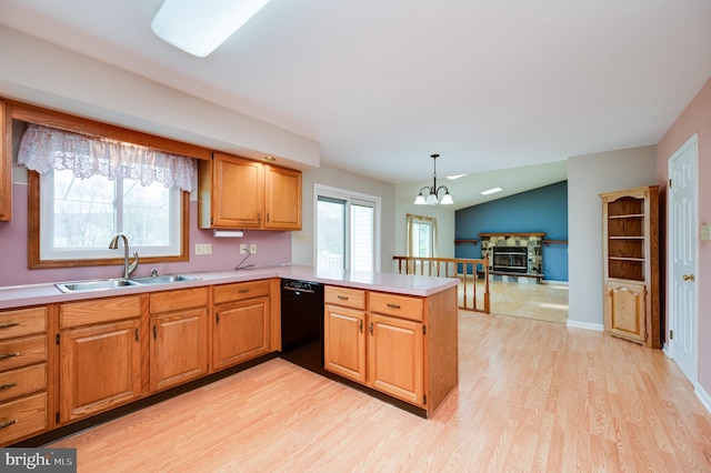 kitchen featuring light wood-type flooring, a sink, light countertops, a peninsula, and black dishwasher