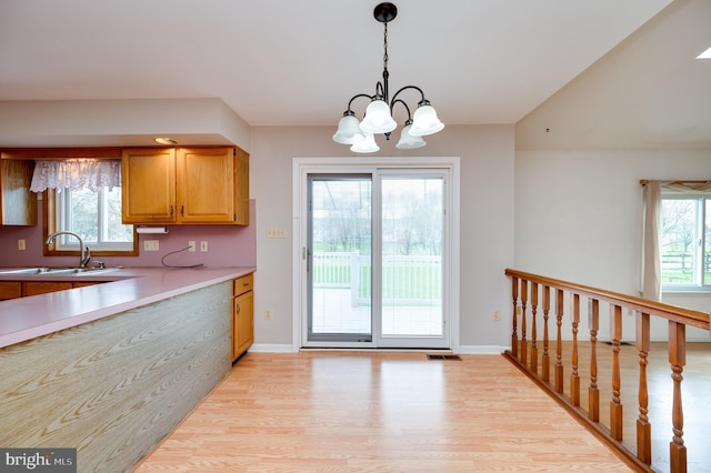 kitchen with a sink, a notable chandelier, light wood-style flooring, and a wealth of natural light