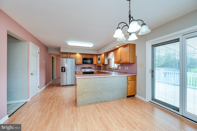 kitchen featuring an inviting chandelier, black microwave, light wood-style floors, range with electric stovetop, and stainless steel fridge