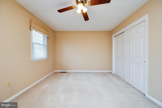 unfurnished bedroom with a closet, carpet, baseboards, and a ceiling fan