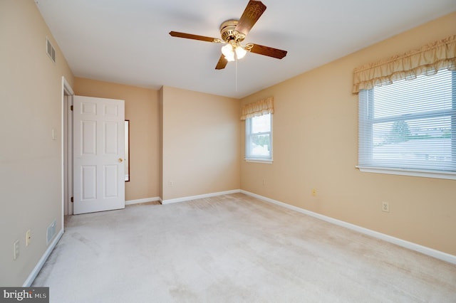 carpeted empty room with visible vents, baseboards, and ceiling fan