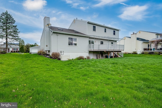 rear view of house featuring a yard, a chimney, and a wooden deck