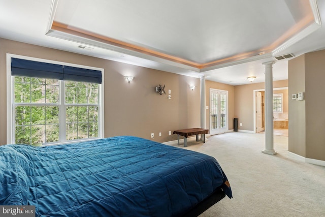bedroom with multiple windows, light carpet, a tray ceiling, and ornate columns