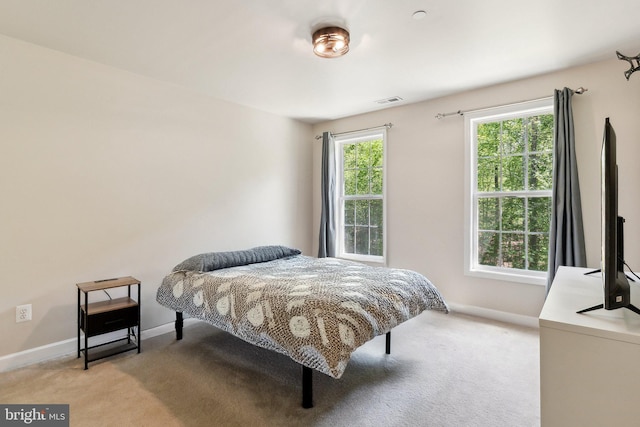bedroom with baseboards, visible vents, and light carpet