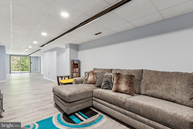 living area featuring recessed lighting, baseboards, wood finished floors, and a drop ceiling