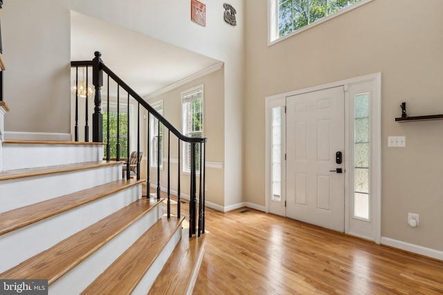foyer featuring baseboards, a wealth of natural light, stairway, and wood finished floors