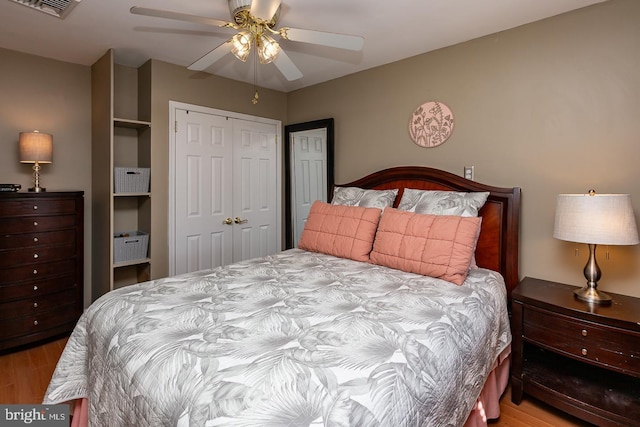 bedroom featuring a ceiling fan, a closet, wood finished floors, and visible vents