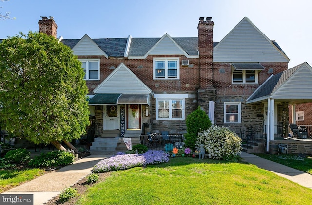 multi unit property featuring brick siding, a front lawn, stone siding, and a chimney