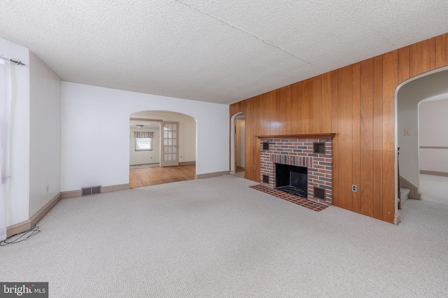 161 E Ave, Woodstown, NJ 08098 - unfurnished living room featuring carpet floors, arched walkways, wood walls, a brick fireplace, and a textured ceiling