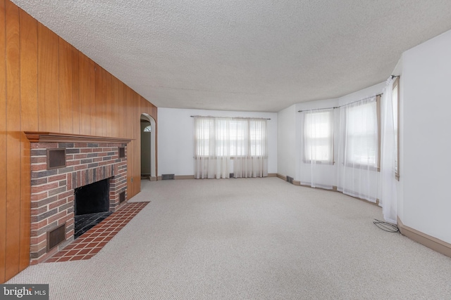 161 E Ave, Woodstown, NJ 08098 - unfurnished living room with arched walkways, a brick fireplace, carpet floors, wood walls, and a textured ceiling
