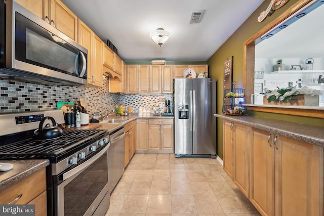 kitchen with light brown cabinetry, dark countertops, a sink, stainless steel appliances, and tasteful backsplash