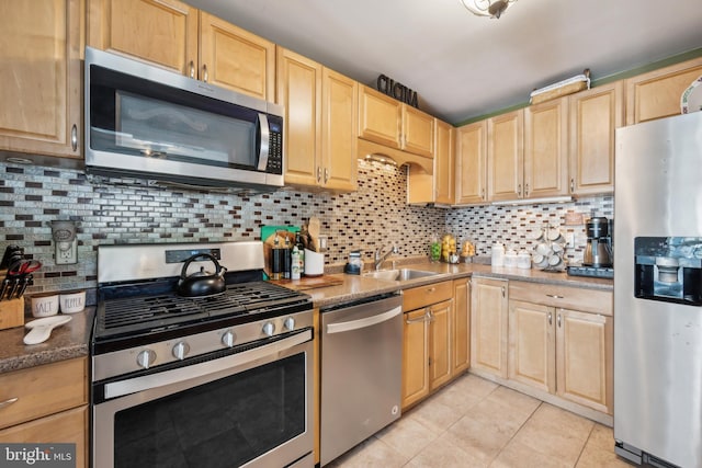kitchen with decorative backsplash, a sink, light tile patterned floors, light brown cabinets, and stainless steel appliances